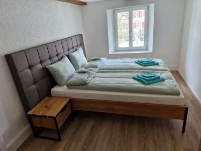 Gästezimmer mit Doppelbett, Holz-Nachttisch und Fenster
