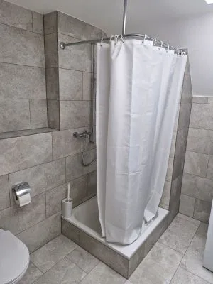 Dusche mit Vorhang in grauen Fliesen