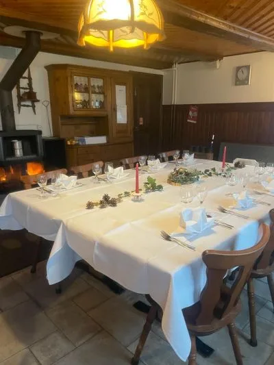 Gaststube mit gedecktem Tisch, Kachelofen und Buffetschrank aus Holz