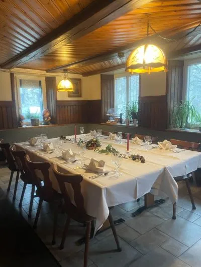 Gaststube mit Holzdecke, Hängelampe und langer, festlich gedeckter Tafel