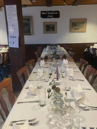 Lange gedeckte Tafel in der Albert-Schweizer-Stube mit Landschaftsbildern an der Wand