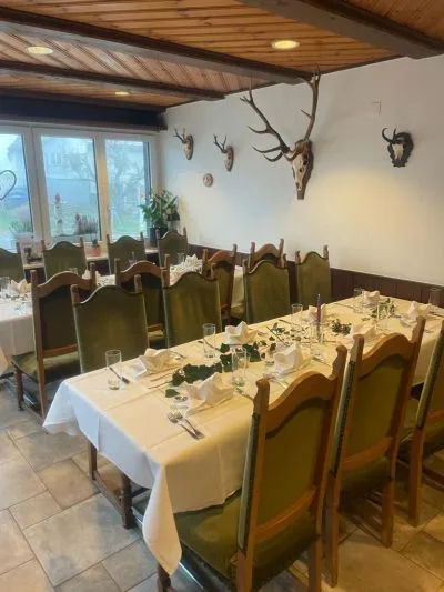 Säli mit olivgrünen Polsterstühlen, Geweihen an der Wand und gedeckter Tafel